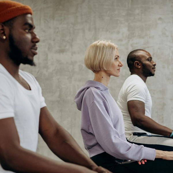 Diverse group of people smiling during a light yoga practice indoors.